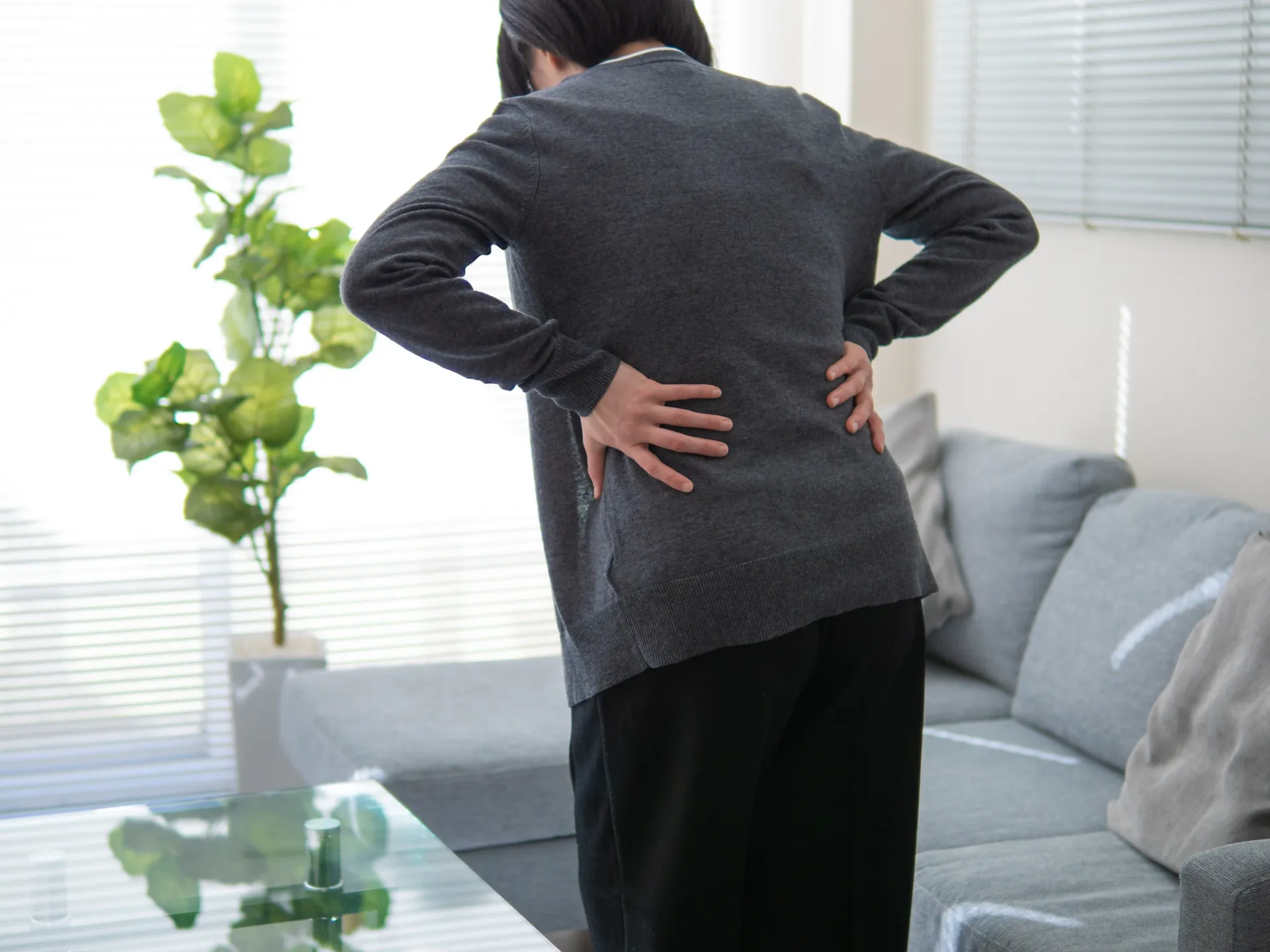 腰痛に悩む女性。白山・本駒込のマシンピラティス×パーソナルジムSTAND TALLでは、正しい運動パターンを身に着け根本改善を目指します。